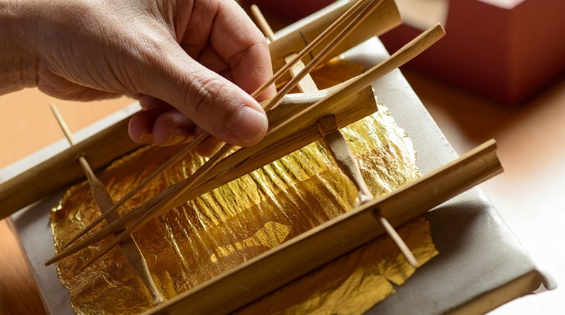金箔の箔打ち道具（箔挟み）で金箔を慎重に扱う職人の手元