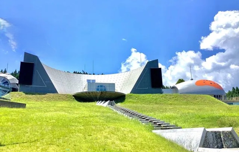 石川県能登島ガラス美術館の外観。宇宙基地のような独創的な建物と緑の丘・青空のイメージ画像
