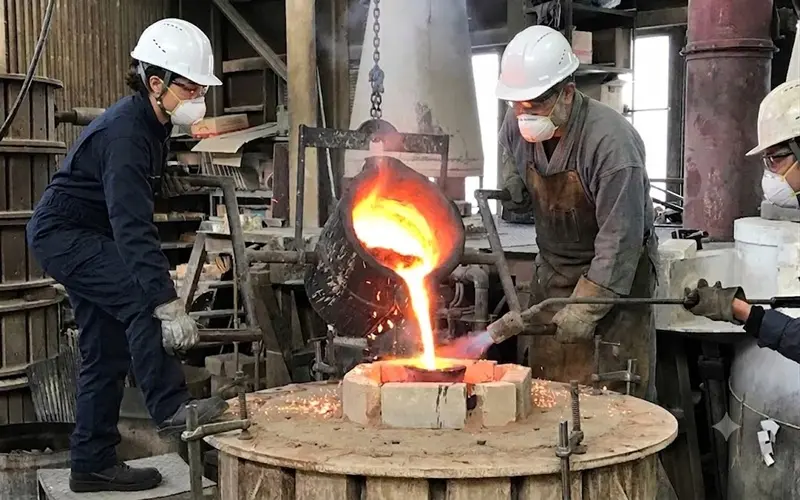 高岡銅器の鋳造工程 現代の職人が砂型に溶けた金属を流し込む